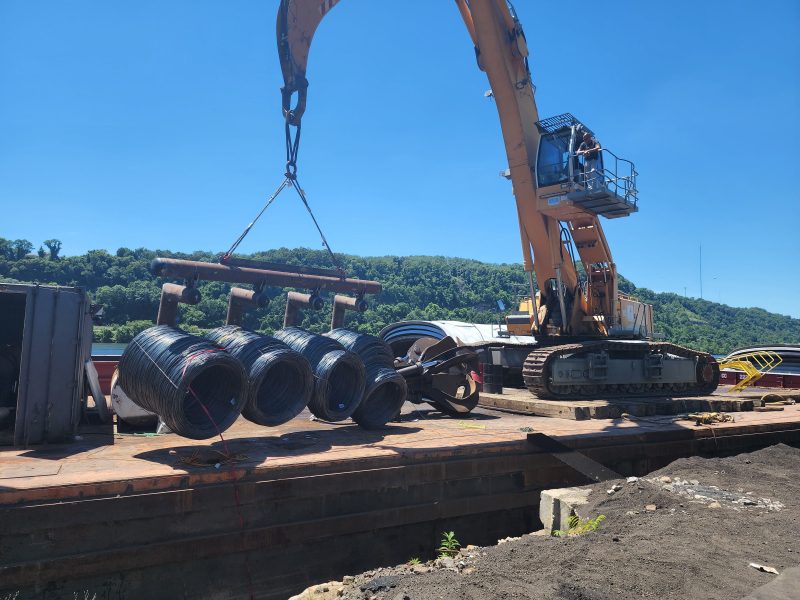 Steel wire coils being offloaded from barge to truck.